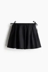 Pollera mini de corte circular en tejido liviano, con cintura elástica y tiras decorativas para atar en los laterales.