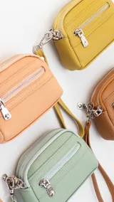 Monedero de dama con correa de mano, confeccionado en material símil cuero con textura granulada. Cuenta con doble compartimento principal con cierre y un bolsillo frontal con cierre, ideal para organizar tarjetas, billetes y monedas.