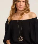 Blusa negra de viscosa con escote off-shoulder, mangas 3/4 con elásticos y lazos en los puños.