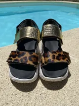 Sandalias con plataforma blanca, tiras de cuero con estampado animal print y tira trasera de cuero negro con hebilla dorada.