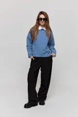 Pantalón sastrero de pierna amplia, color negro, con tiro medio, cintura con pasacintos, cierre frontal con botón y cremallera, bolsillos laterales y bolsillos ojal decorativos en la parte posterior.