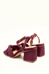 Sandalia de tacón cuadrado medio, confeccionada en terciopelo negro. Presenta un diseño de tiras cruzadas con nudo en la parte delantera y una tira ajustable con hebilla en el tobillo.