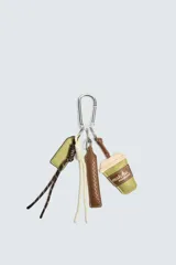 Llavero con mosquetón metálico que incluye múltiples charms colgantes: una etiqueta verde, cordones de colores, una tira de cuero trenzado y un dije en forma de vaso con la inscripción 'matcha moment'.