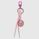 Llavero tipo charm para bolso con cordón trenzado en tonos rosa y blanco, mosquetón metálico fucsia y dije circular con logo de la marca en color verde lima.