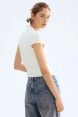 Top de punto suave color blanco, de manga corta con cuello alto y ajuste ceñido.