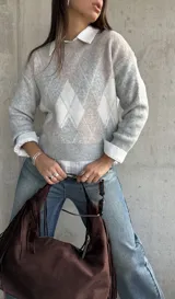 Sweater de punto con diseño de rombos en tonos gris y beige, cuello redondo, mangas largas y puños acanalados.
