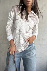 Sweater de punto con diseño floral en tonos beige y blanco, cuello tipo polo y mangas largas.