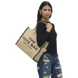 Bolso tipo tote de gran tamaño en color beige, confeccionado en lona resistente. Presenta el logo estampado en negro en el frente y detalles de ribetes negros en los bordes. Incluye asas superiores para llevar al hombro.