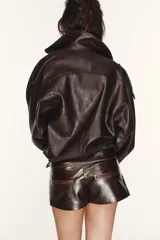 Shorts de tiro bajo confeccionados en material con acabado efecto cuero brillante. Presentan cintura ancha con detalle de botones forrados en el frente y cierre frontal con cremallera.