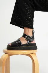 Sandalias negras de cuero con plataforma y hebillas plateadas.