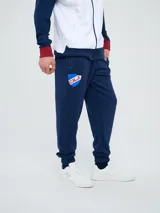 Pantalón deportivo azul marino con puños elásticos en los tobillos, bolsillos laterales con cierre, escudo del Club Nacional de Football en una pierna y logo de Umbro en la otra.