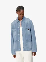 Campera de denim estilo chore coat, con cuatro bolsillos frontales, cierre de botones metálicos y etiqueta de la marca en el bolsillo superior izquierdo. Presenta un corte holgado y costuras en contraste.