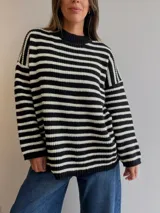 Sweater de tejido de punto con diseño a rayas horizontales en blanco y negro, de corte holgado, cuello redondo y mangas largas.