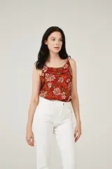 Musculosa color ladrillo con estampado de flores blancas y hojas verdes, breteles finos y escote redondo.