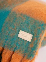 Bufanda larga con flecos, con diseño a cuadros grandes en tonos naranja, verde agua y lila.