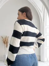 Sweater de punto a rayas horizontales anchas en blanco y negro, con cuello redondo y mangas largas.