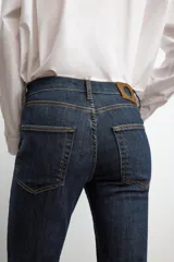 Jeans de mezclilla azul claro, tiro medio, corte recto y ligeramente acampanado en el bajo. Presenta cinco bolsillos y cierre frontal con cremallera y botón metálico.