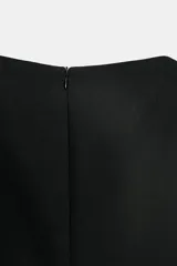 Top color crema de cuello redondo y manga corta abullonada. Presenta un bajo asimétrico y cierre en la espalda con cremallera oculta en la costura.