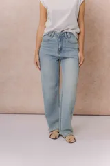 Jean wide leg de tiro medio-alto en denim azul medio con lavado desgastado. Presenta diseño de cinco bolsillos, cierre con botón y cremallera, y pierna amplia de caída recta.
