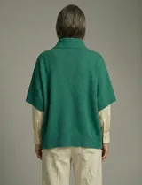 Capa tejida color fucsia, con cuello alto abotonado y mangas cortas estilo japonesa. Tejido de punto grueso.