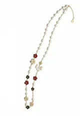 Collar largo compuesto por perlas de diferentes formas intercaladas con apliques de flores y moños de resina esmaltada en tonos rojo, negro y crema. Cuenta con cadena de alargue metálica.