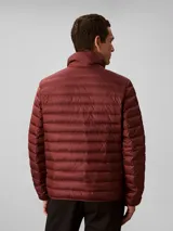 Campera puffer ligera de Calvin Klein, color bordó, con acolchado de canales horizontales, cuello alto y cierre frontal de cremallera. Presenta un diseño minimalista con logo de la marca en el pecho.