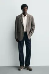 Zapatilla deportiva color verde militar, con parte superior de múltiples piezas que combinan piel y serraje. Presenta horma redonda y suela dentada en color crema con base marrón.