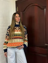 Sweater de lana merino con estampado Fair Isle en tonos azul marino, beige, naranja, verde oliva y bordó. Tiene cuello redondo y mangas largas.