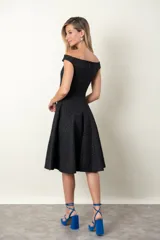 Vestido negro con textura en relieve, falda acampanada y escote con abertura.