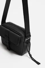 Bandolera color verde militar con acabado engomado, correa de hombro ajustable y extraíble, compartimento principal con cierre de cremallera, bolsillo interior con cremallera y bolsillo frontal con cierre de hebilla de liberación rápida.