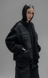 Campera estilo bomber unisex, confeccionada en una combinación de corderito sintético y paneles de ripstop. Presenta un diseño utilitario con múltiples bolsillos frontales con cierres y broches a presión, cuello, puños y ruedo en ribb elástico.