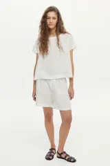 Blusa de lino color blanco, con cuello bote y mangas cortas de corte holgado.