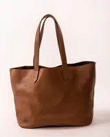 Bolso tote de cuero color tostado, con doble asa de hombro y diseño minimalista. Incluye un bolsillo separador extraíble.