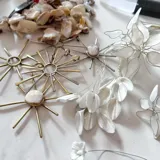 Colgante dorado con forma de sol, con rayos lisos y centro con piedra blanca.