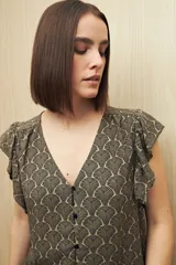 Blusa estampada con motivos de hojas en tonos beige y negro, con escote en V, botones al frente y volados en los hombros.