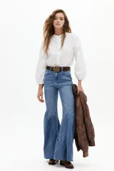 Pantalón de jean azul con corte acampanado y vuelo pronunciado en el ruedo, de tiro alto.