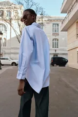 Camisa de corte oversize con cuello solapa, manga larga con puños y bajo asimétrico. Cierre frontal con botones.