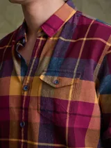 Camisa de manga larga en color azul noche con un patrón de cuadros finos en tonos rojos y verdes. Presenta cuello clásico, cierre frontal con botones y un bolsillo en el pecho con solapa.