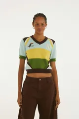 Top tejido de manga corta confeccionado en punto de algodón. Presenta escote en V, diseño de bloques de color en celeste, amarillo, verde y marrón, con detalles bordados en el frente y número 10.