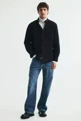 Camisa de algodón estilo Oxford, color negro, con cuello americano abotonado, bolsillo en el pecho y cierre frontal con botones blancos.