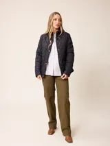 Campera acolchada de diseño matelassé, color negro, con cuello alto, cierre frontal con cremallera y botones a presión, y bolsillos delanteros con solapa.