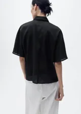 Camisa negra de manga corta, confeccionada en tejido de lino y algodón, con cuello camisero, diseño recto y cierre frontal de botones.