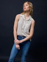 Blusa color crema sin mangas, con cuello camisero, cierre frontal con botones y bolsillo de crochet.