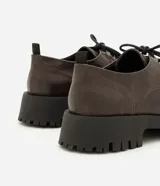 Mocasín tipo dockside color marrón oscuro con acabado texturizado, ajuste frontal con cordones y suela track robusta de goma.