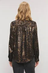 Camisa de satén con estampado animal print tipo leopardo en tonos marrones y negros. Presenta cuello alto con volados, mangas largas con puños abotonados y detalles de volados fruncidos a lo largo de la botonadura frontal.