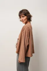 Blusa marrón de corte crop, escote en V y mangas largas anchas. Cierre frontal con lazos.