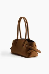 Cartera de hombro color tostado, con doble asa superior y detalle de tiras laterales ajustables. Cuenta con cierre magnético y etiqueta colgante.