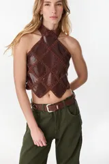 Top halter negro confeccionado con una mezcla de cuero y tejido artesanal, con diseño geométrico de rombos unidos por costuras de crochet y dobladillo en punta.