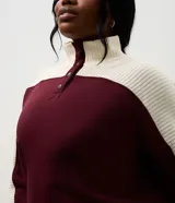Buzo deportivo de corte oversized, con diseño bicolor en bordó y blanco. Presenta cuello alto con cierre de botones a presión, mangas largas con textura acanalada y puños elásticos.
