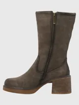 Bota de caña media confeccionada en cuero descarne, con diseño de costuras visibles y taco cuadrado de altura media. Presenta una suela con plataforma y un detalle de tira con hebilla en la parte superior de la caña.